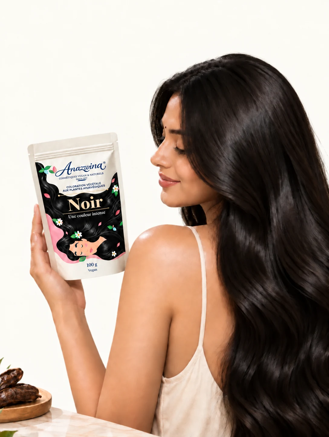 Femme aux cheveux noirs tenant un sachet de coloration végétale Noir Anazwina 100 g.